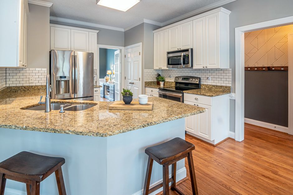 Bright modern kitchen with granite countertop and stainless steel sink, typical under-sink RO installation setting