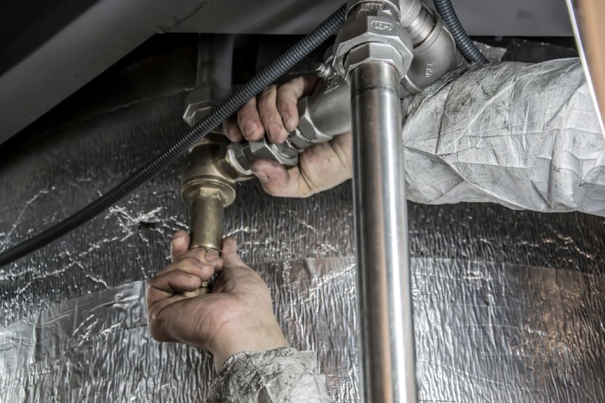 Plumber installing pipe fittings during whole house water filter installation on main water line