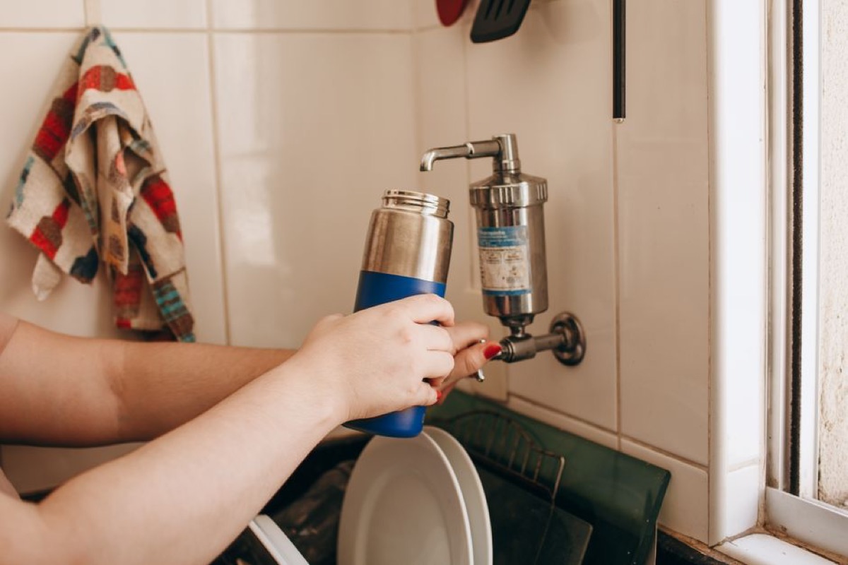Woman preparing water with a filter pitcher in a bright home kitchen
