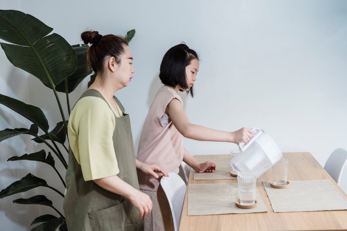 Family using water filter pitcher at kitchen table