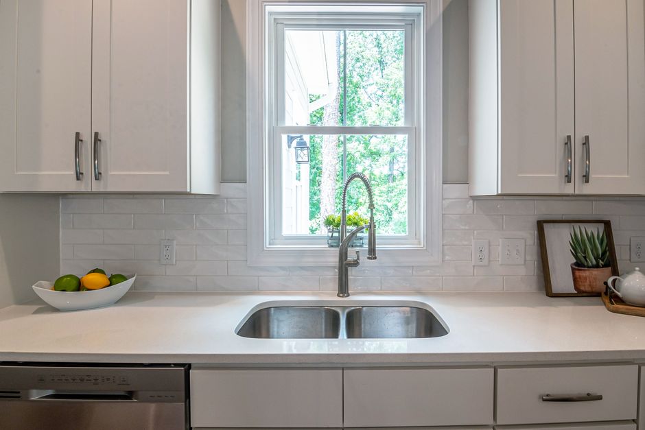 Bright modern kitchen with a stainless steel sink under a window, typical under-sink RO installation location
